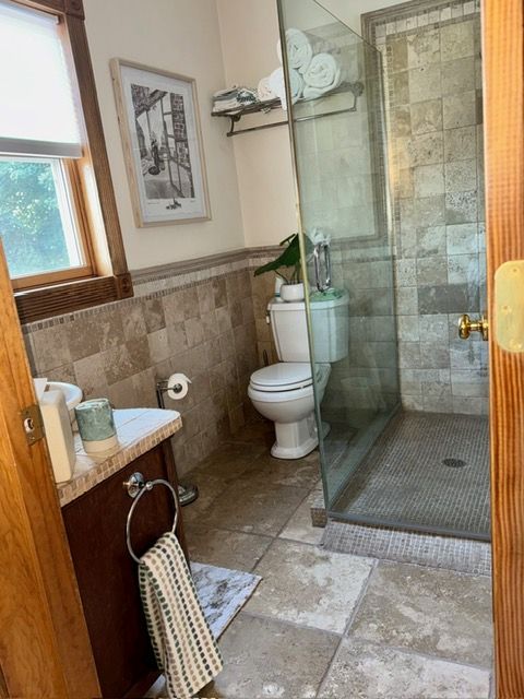A bathroom with a toilet , sink , and walk in shower.