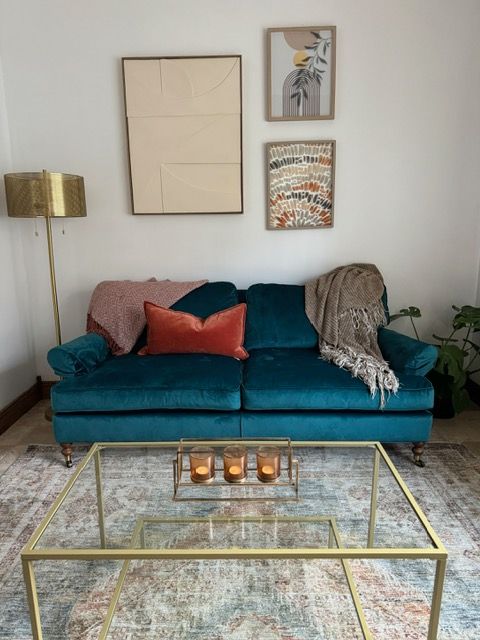 A living room with a blue couch and a glass coffee table