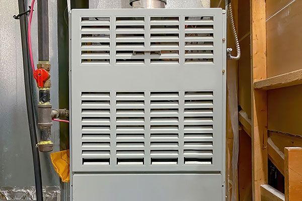 A technician wearing a mask works on an air conditioner unit on a rooftop.