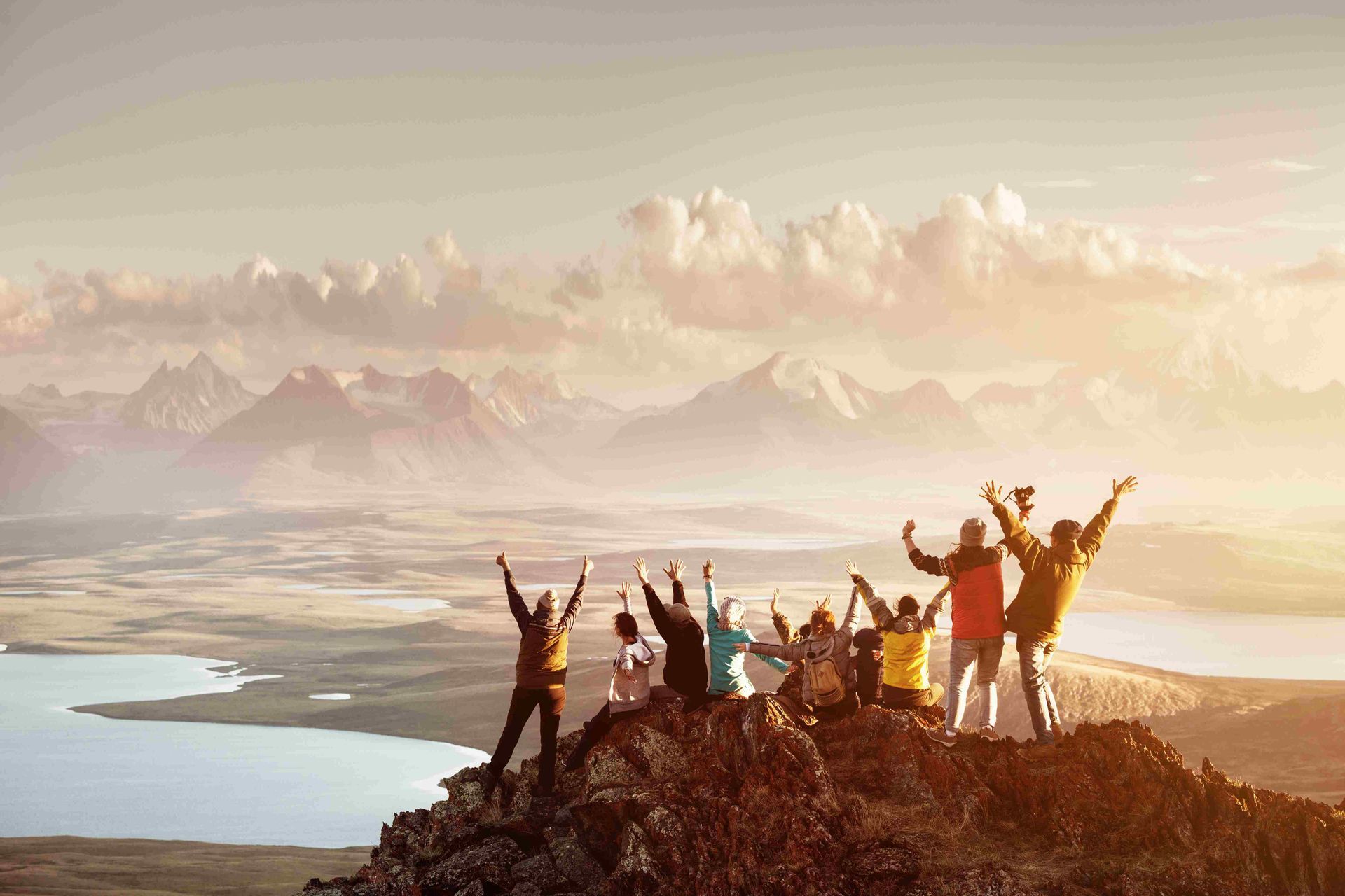 a group of people are sitting on top of a mountain with their arms in the air