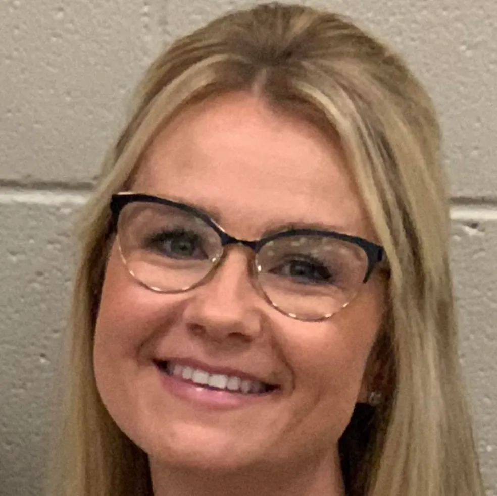 Woman with blonde hair, wearing glasses, smiling.