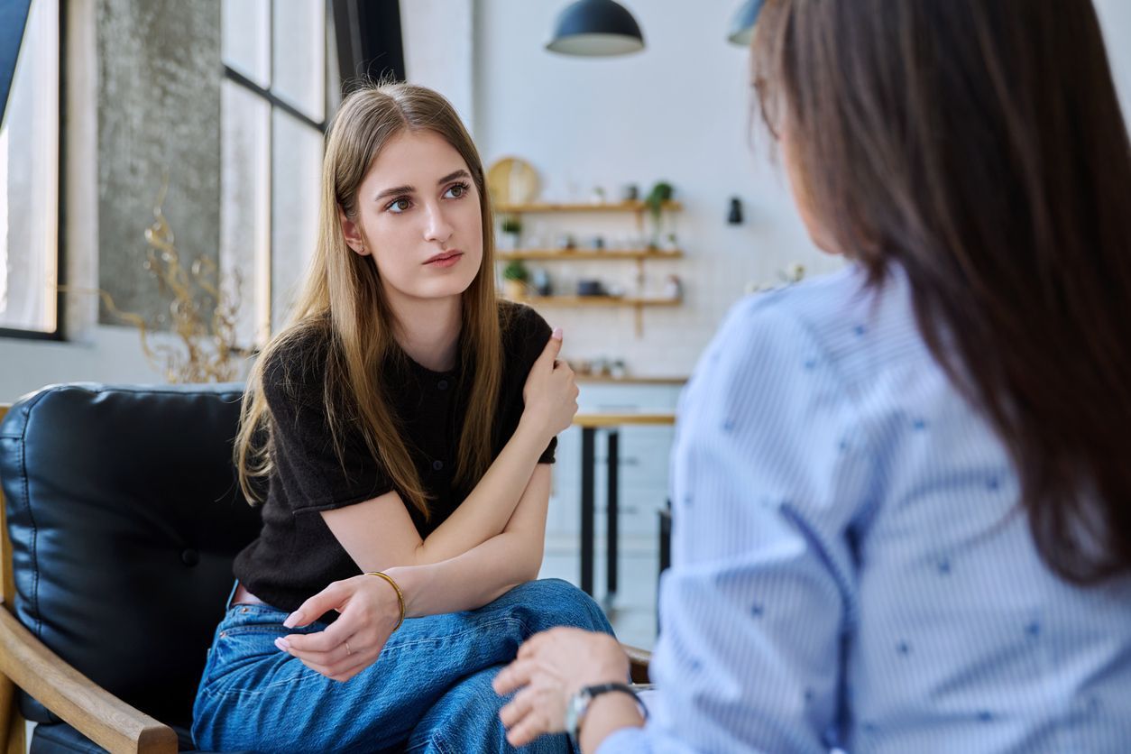 Woman in conversation with another in a counseling setting.
