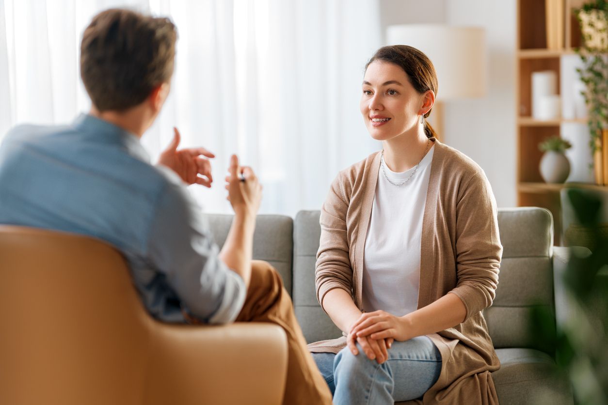Woman smiles while talking to a person in an office setting.