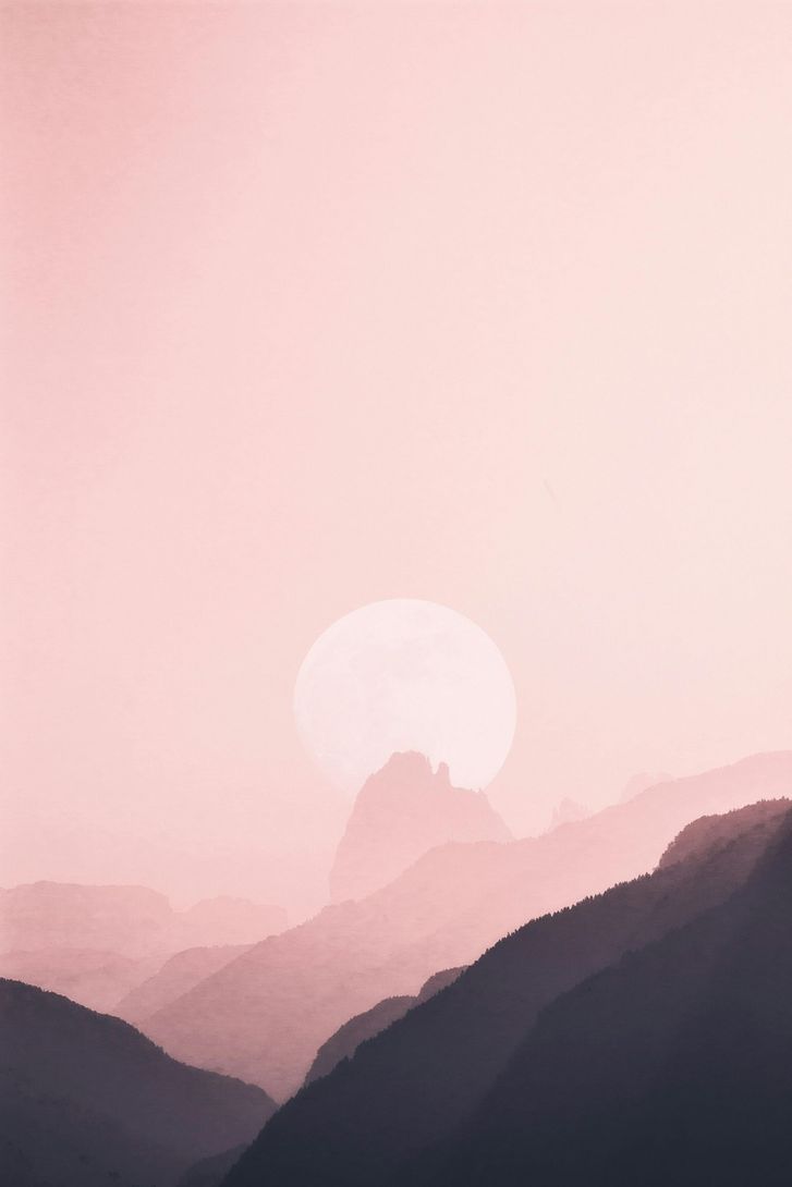 Pink sunset over layered mountain silhouettes.