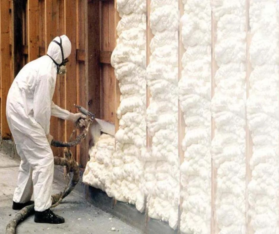 Technician applying closed-cell spray foam insulation to a residential wall cavity.