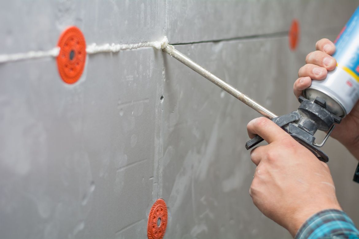 a person is caulking seams on a wall .