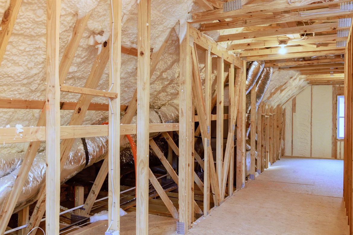 an attic with wooden beams and spray foam on the ceiling .
