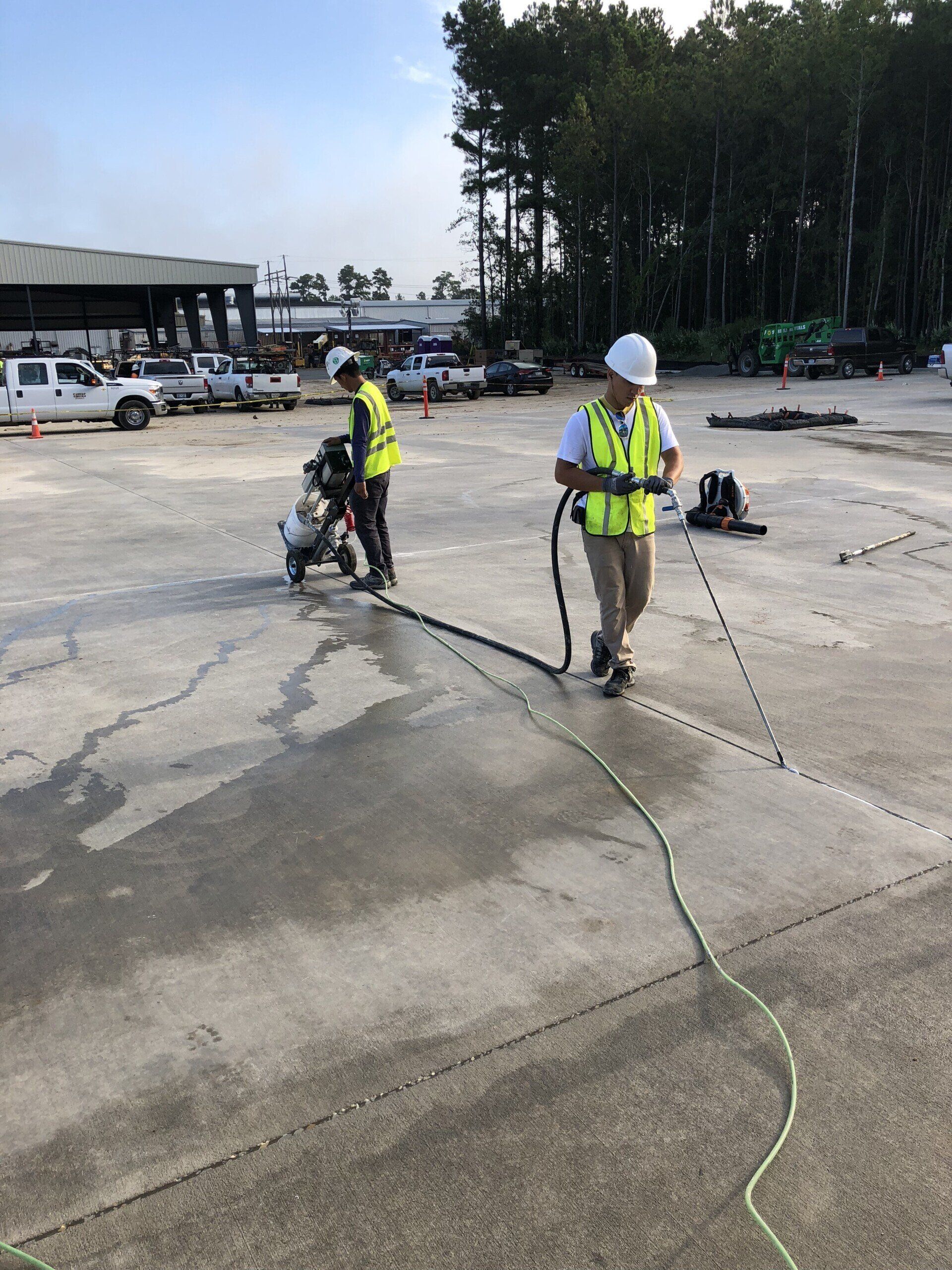 Two men are working on a concrete surface in a parking lot
