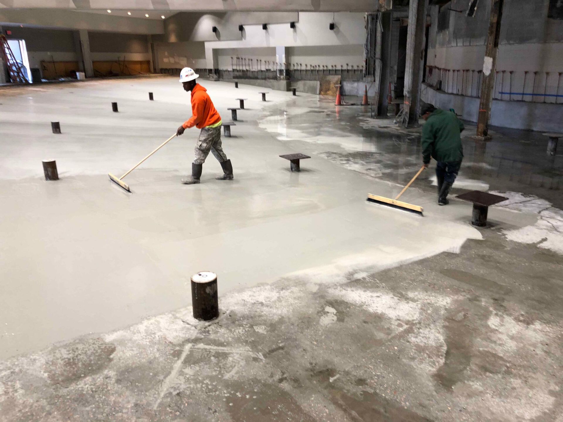 two men are waterproofing a large concrete floor