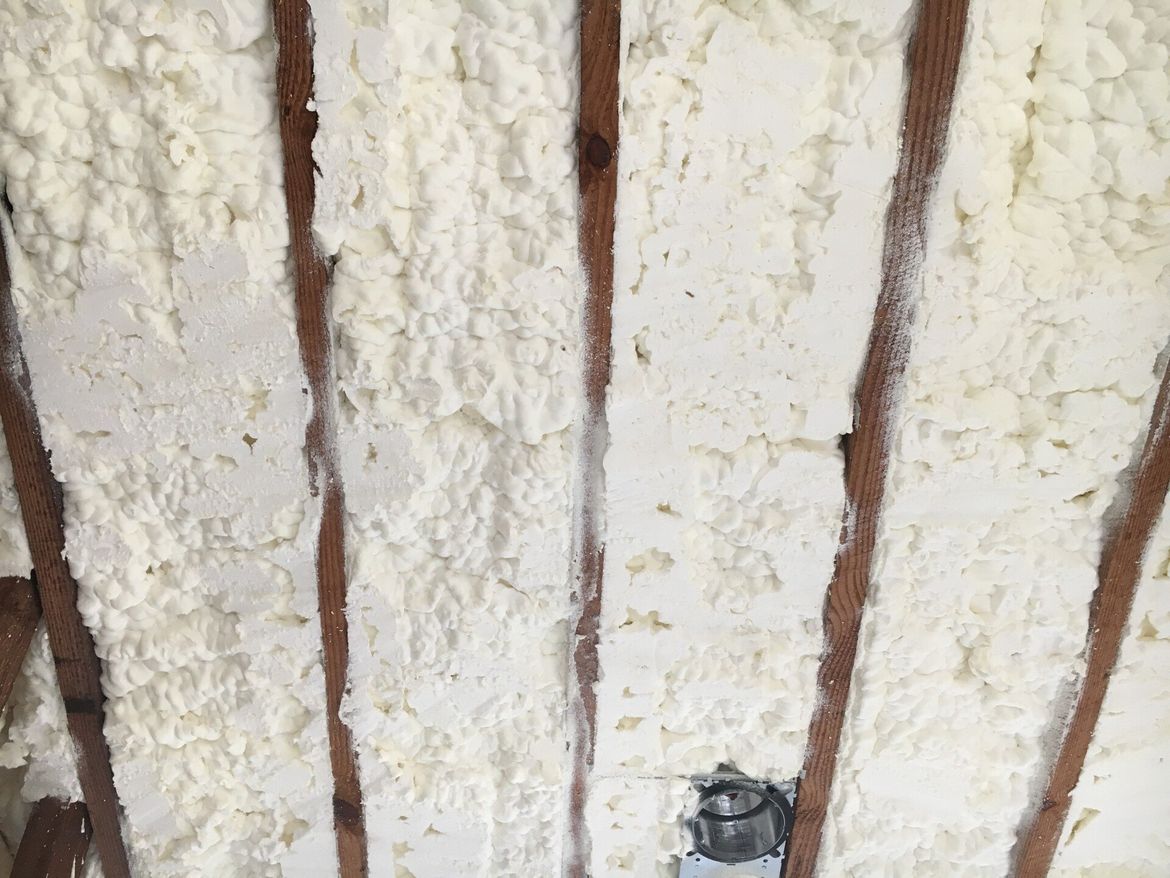 a close up of a wall with spray foam on it and wooden beams .