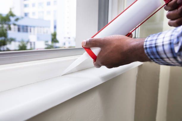 Close-up of silicone caulking being applied around a window frame.
