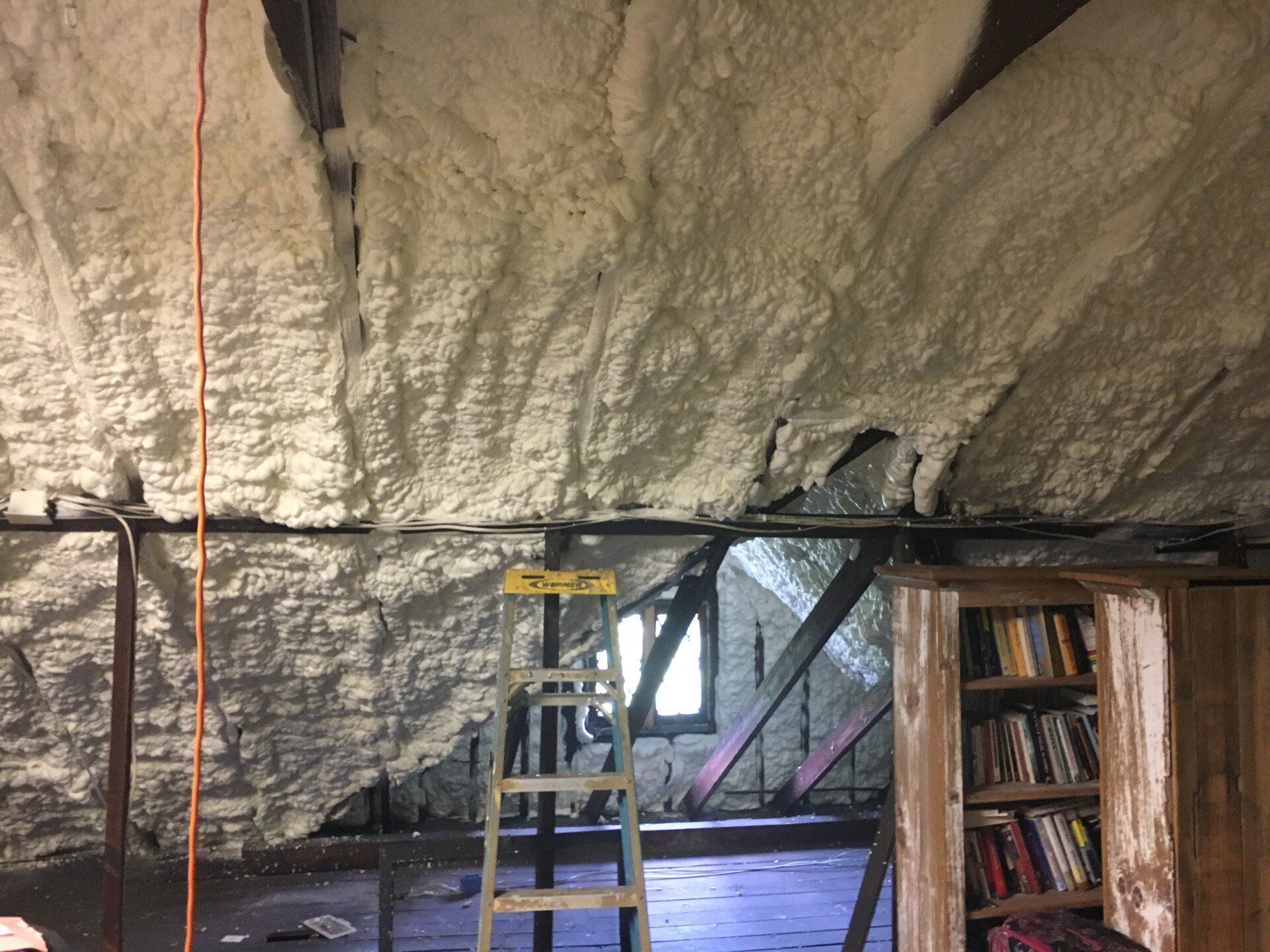 a ladder is sitting in a room with spray foam on the ceiling