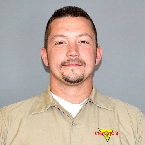 Man with short hair and goatee in tan work shirt, logo 