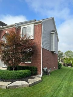 A large brick house with a lush green lawn in front of it.