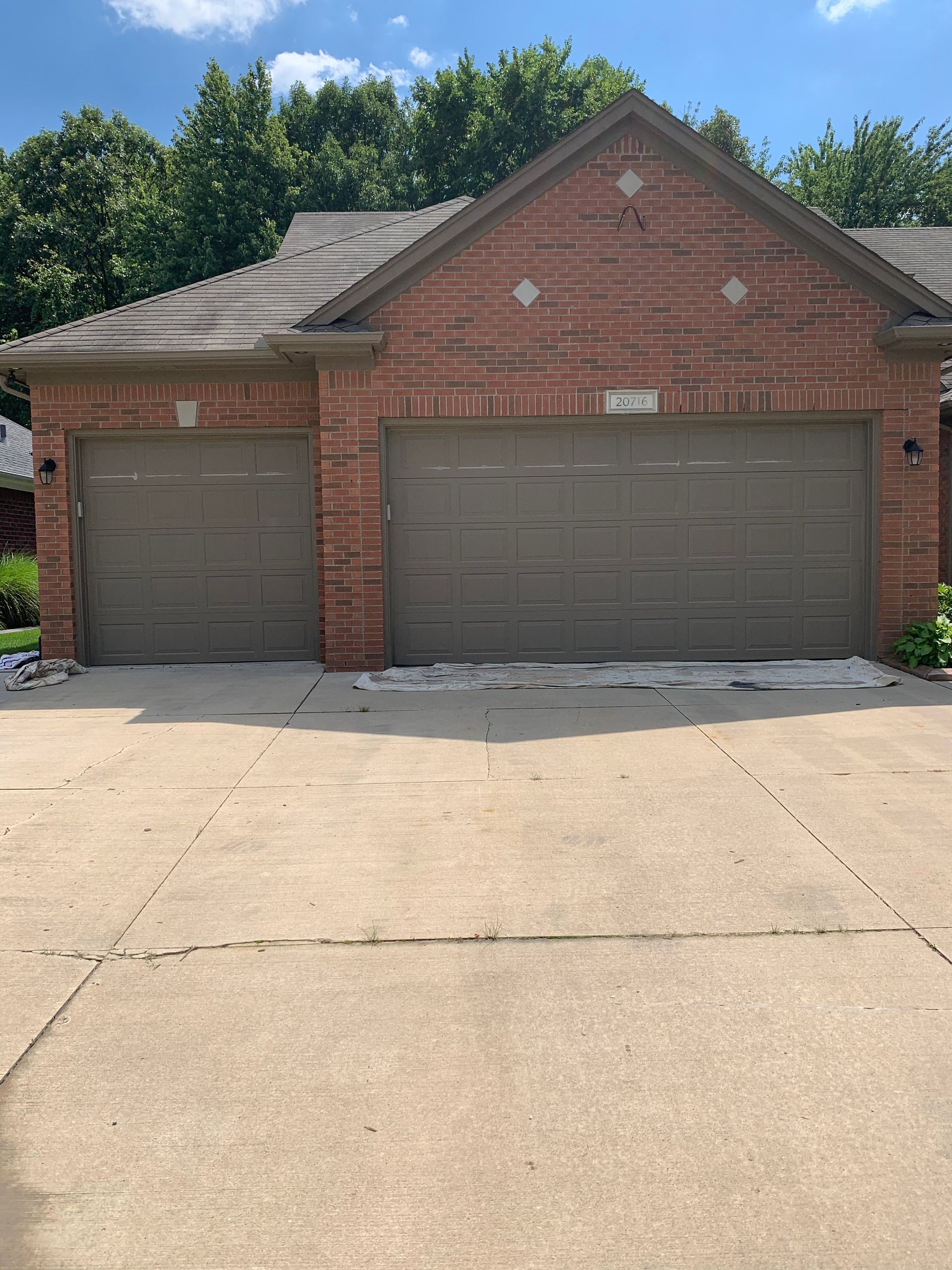 A brick house with three garage doors and a concrete driveway