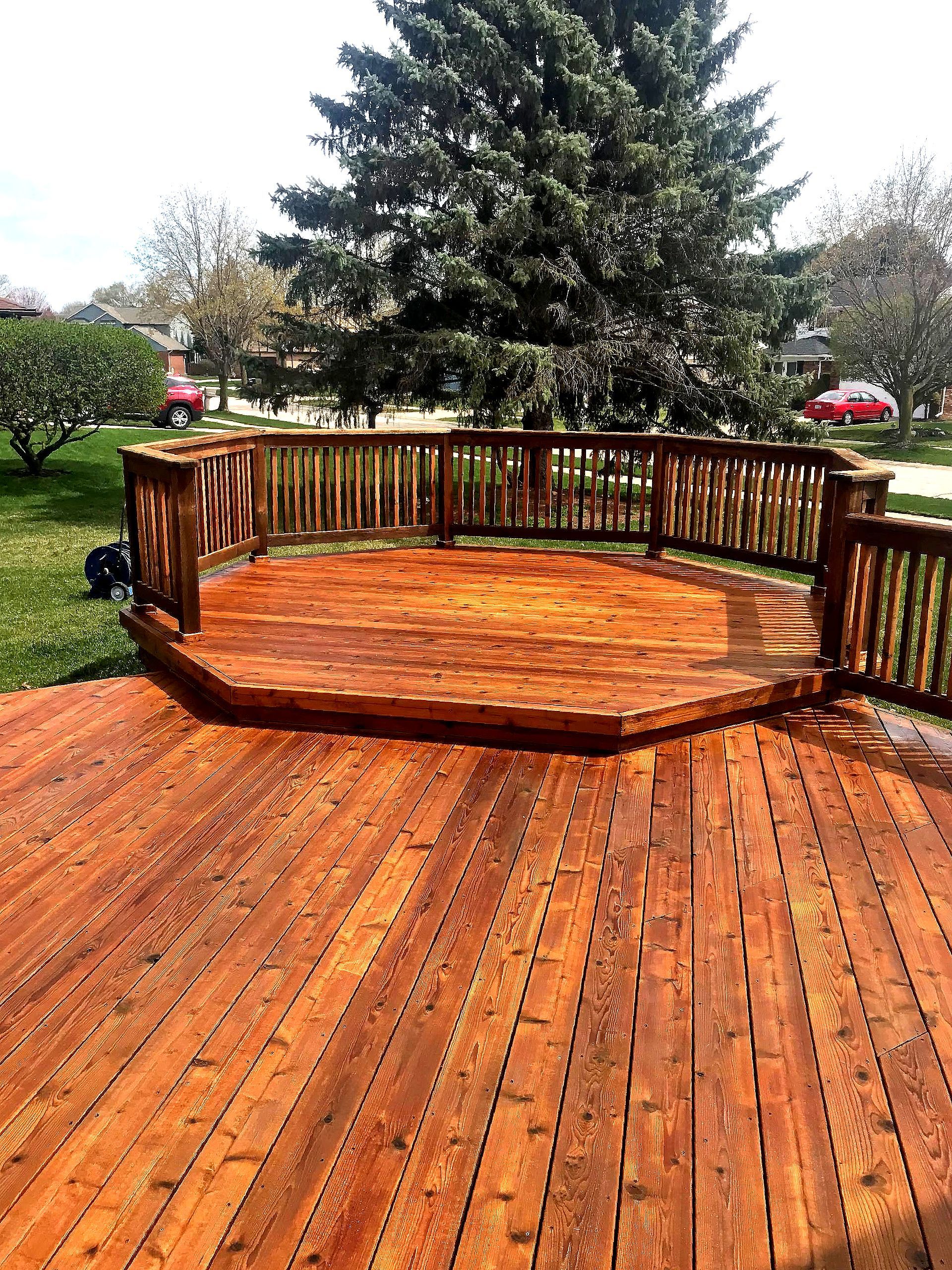 A large wooden deck with a tree in the background.