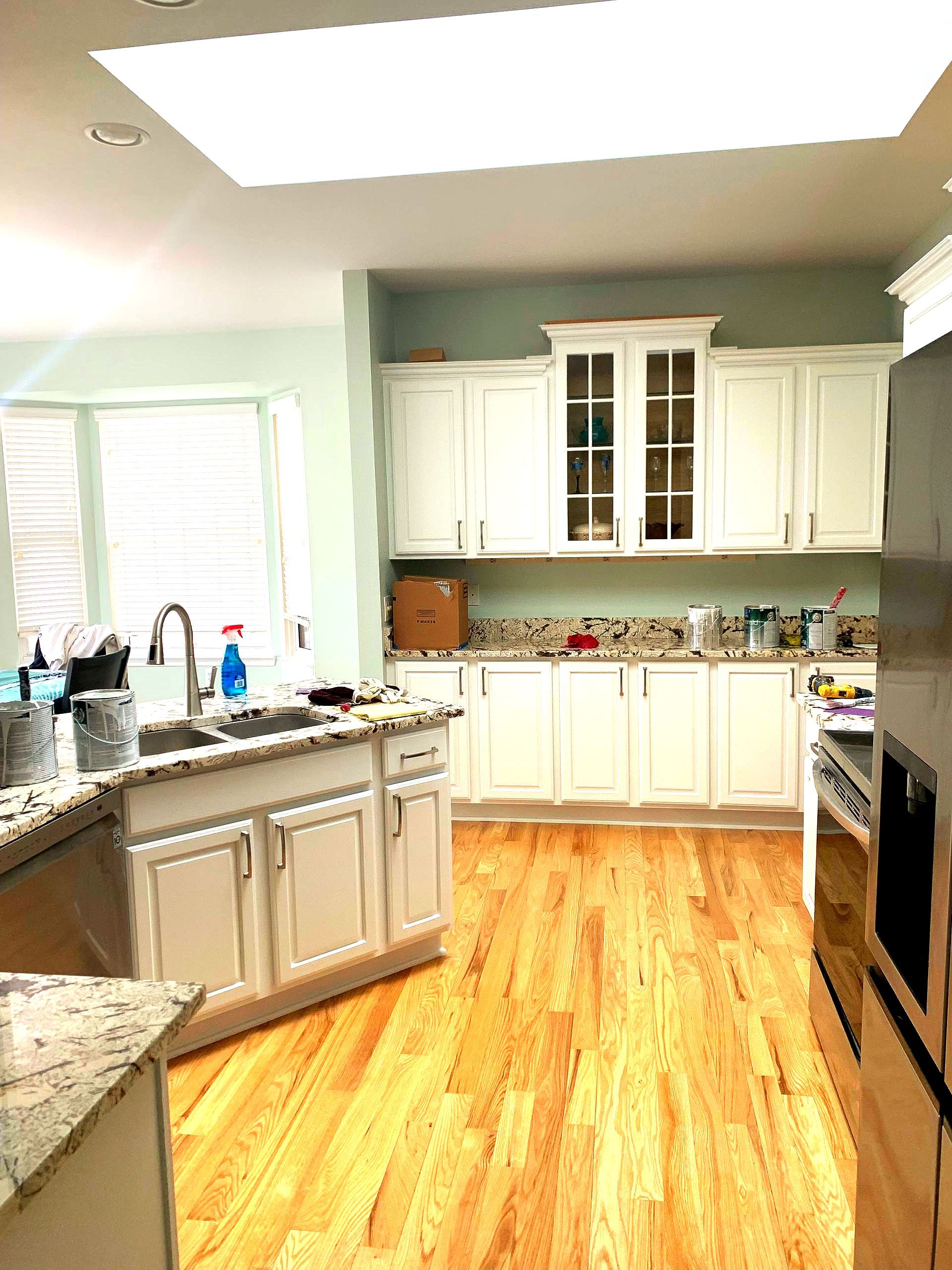 A kitchen with white cabinets and hardwood floors.