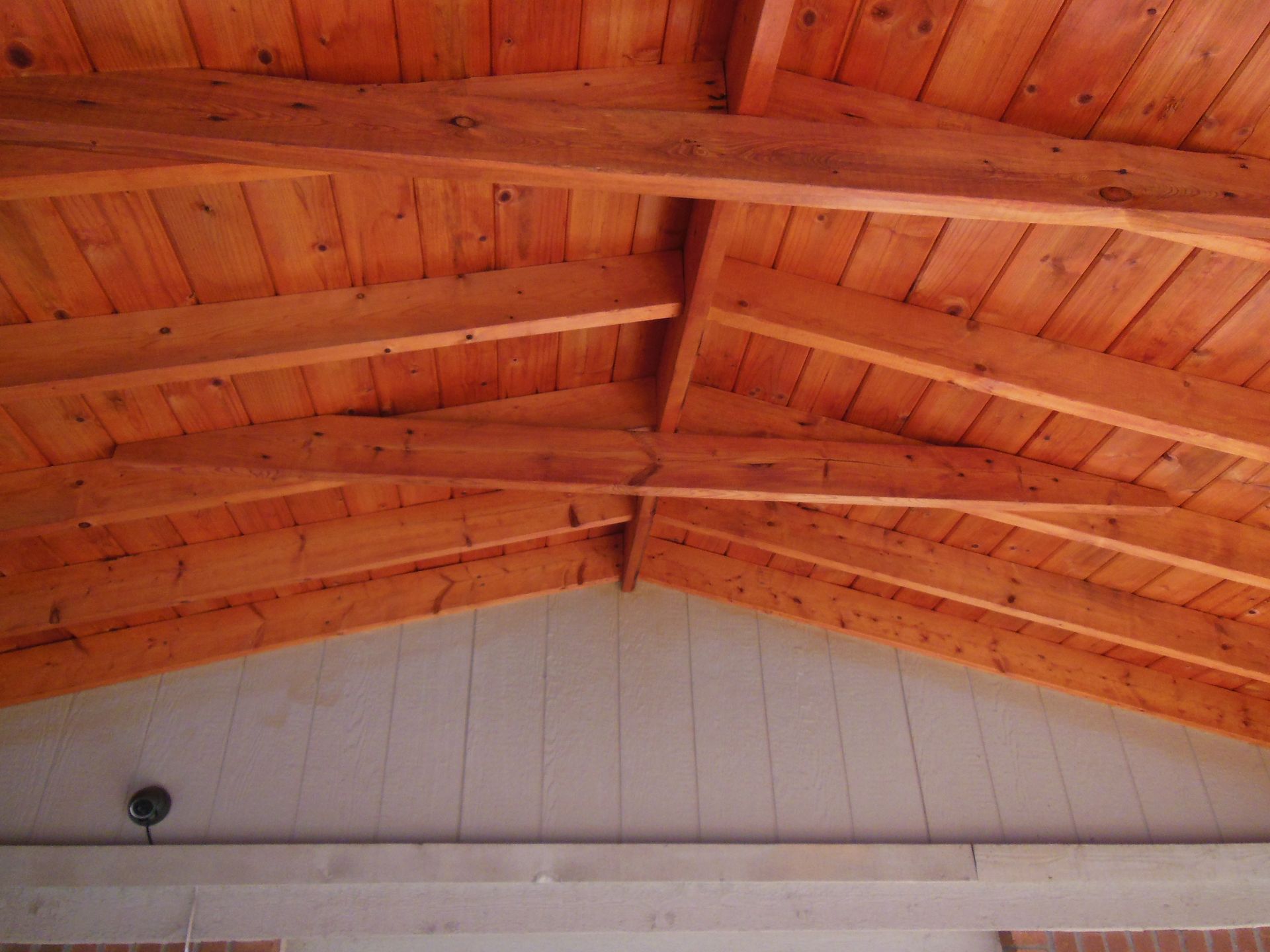 A close up of a wooden ceiling with a ceiling fan hanging from it.