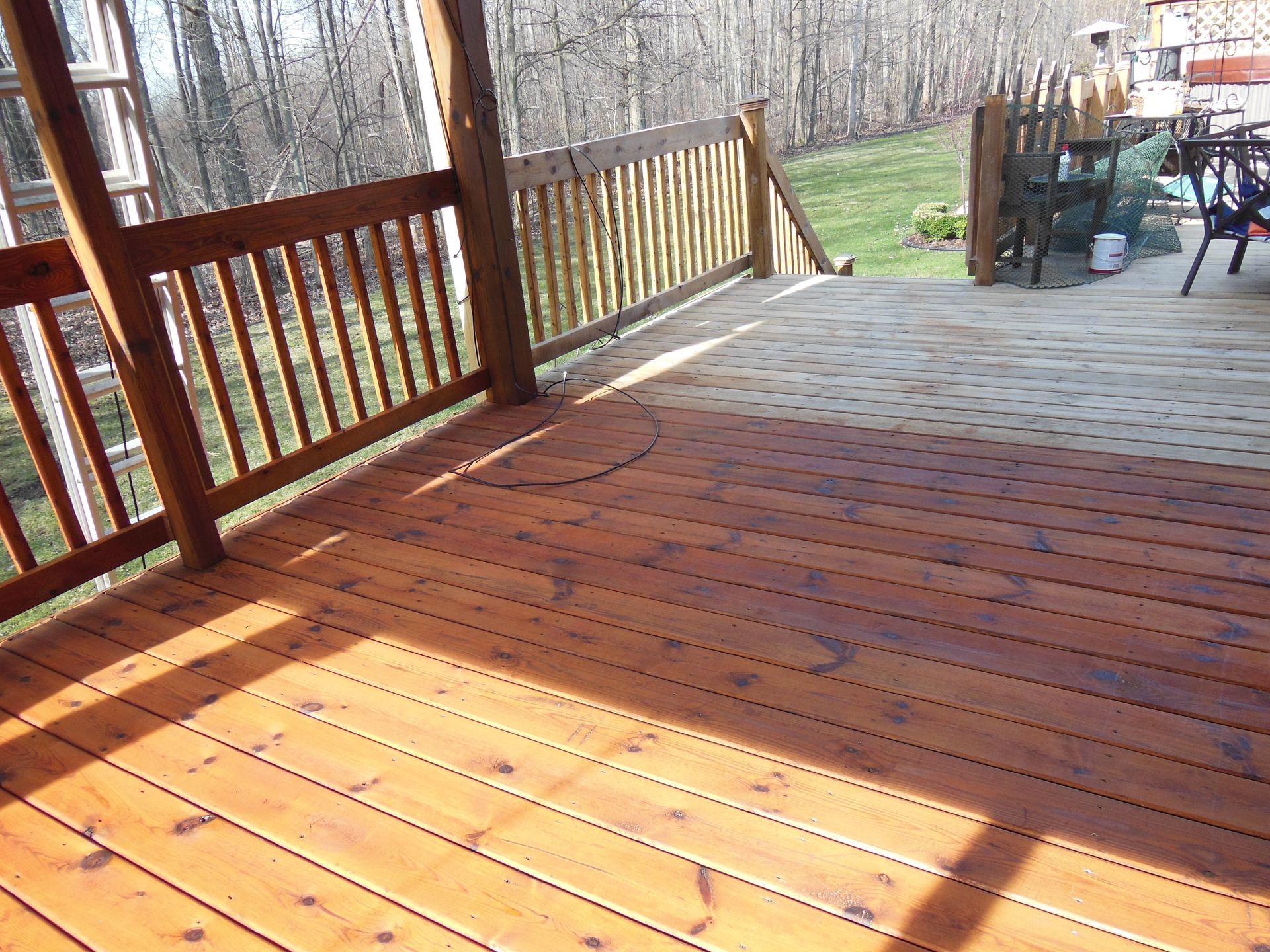 A wooden deck with a railing and a view of the woods