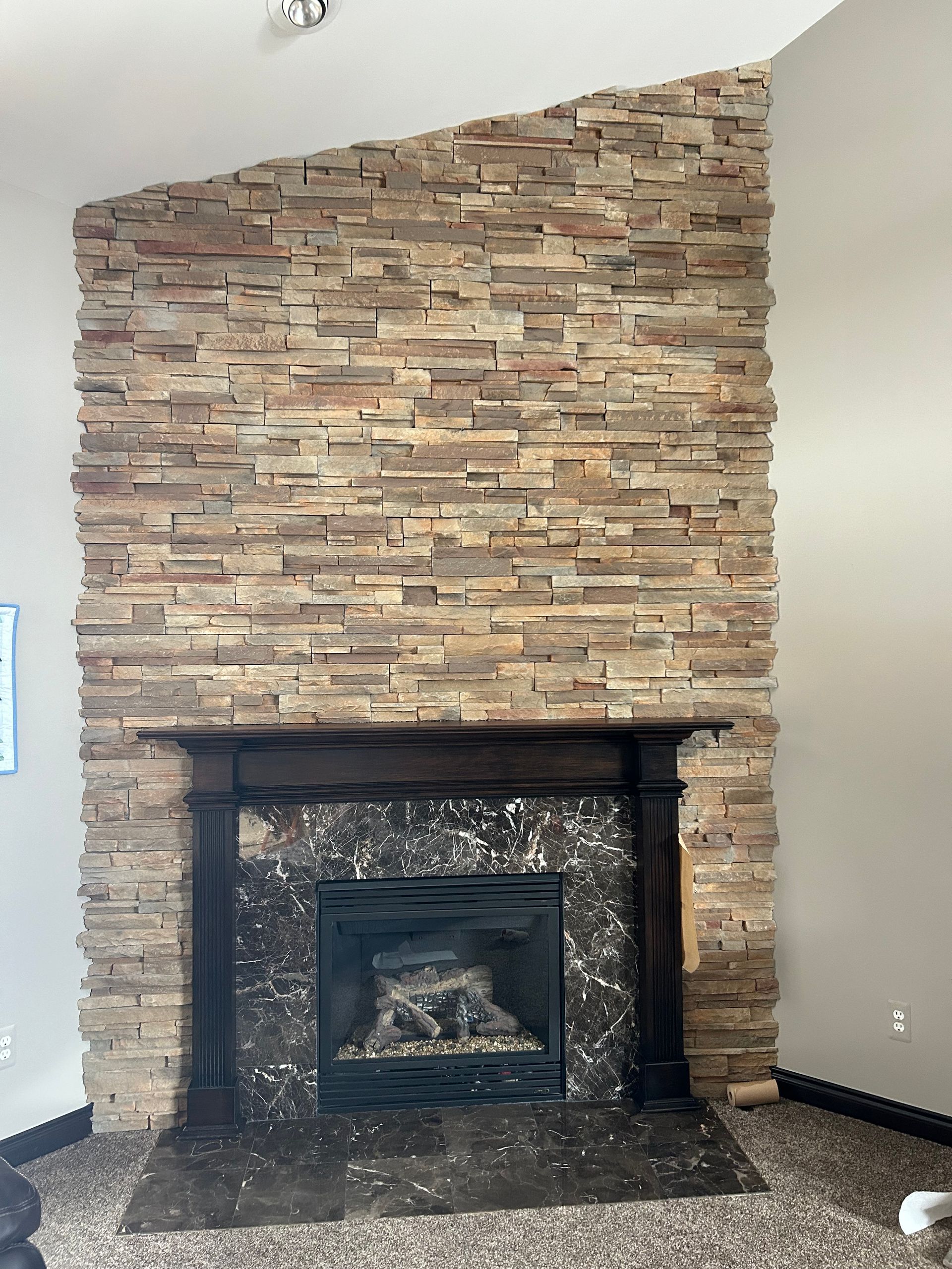 A living room with a fireplace and a stone wall.
