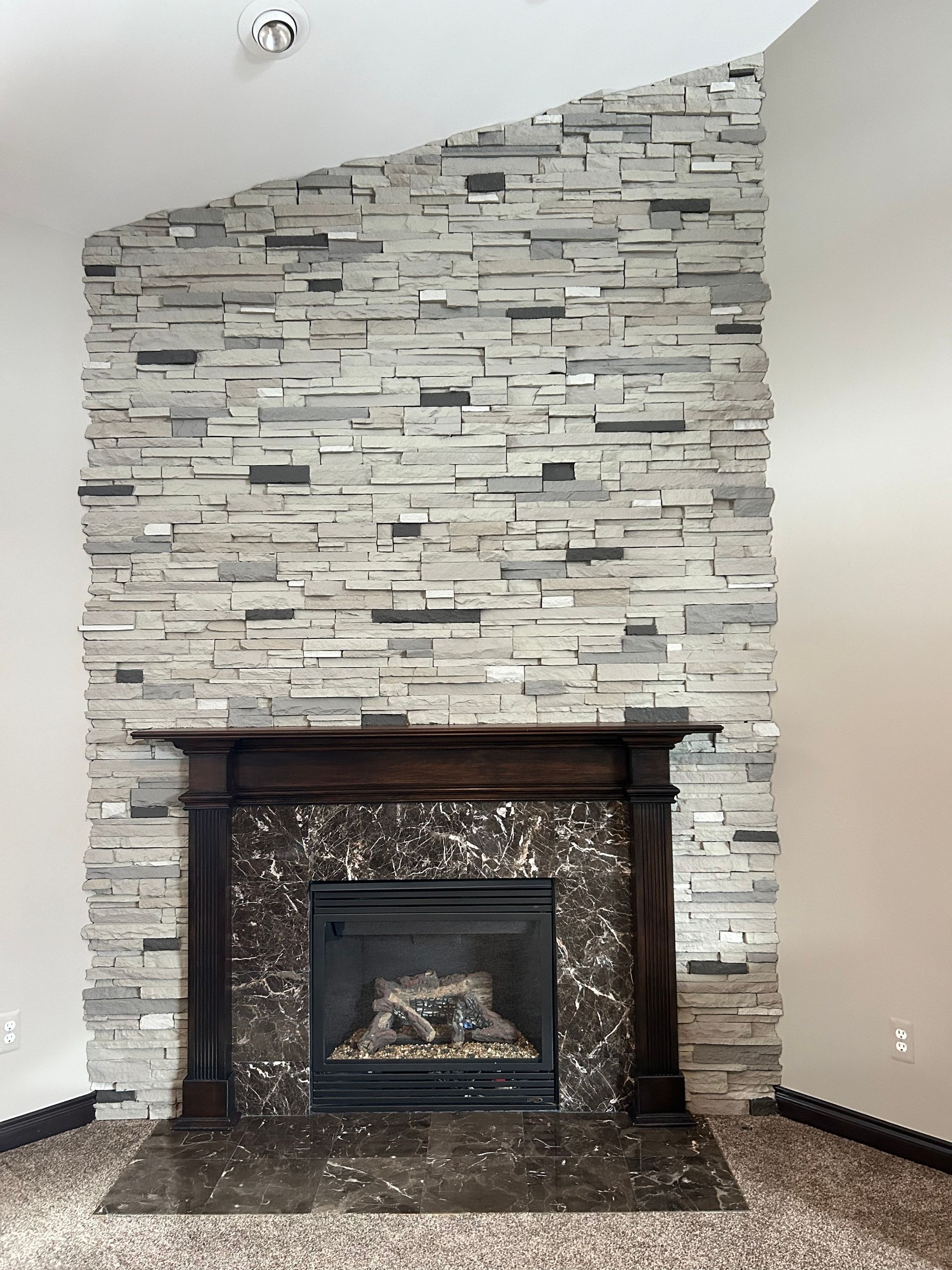 A fireplace in a living room with a stone wall