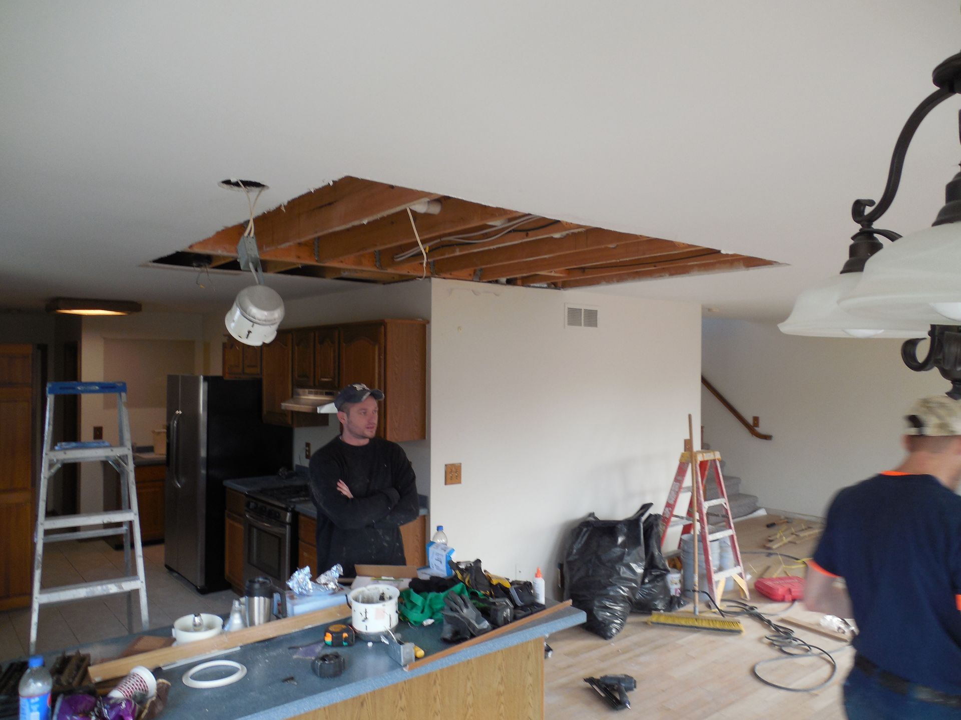 A man standing in a kitchen with a hole in the ceiling