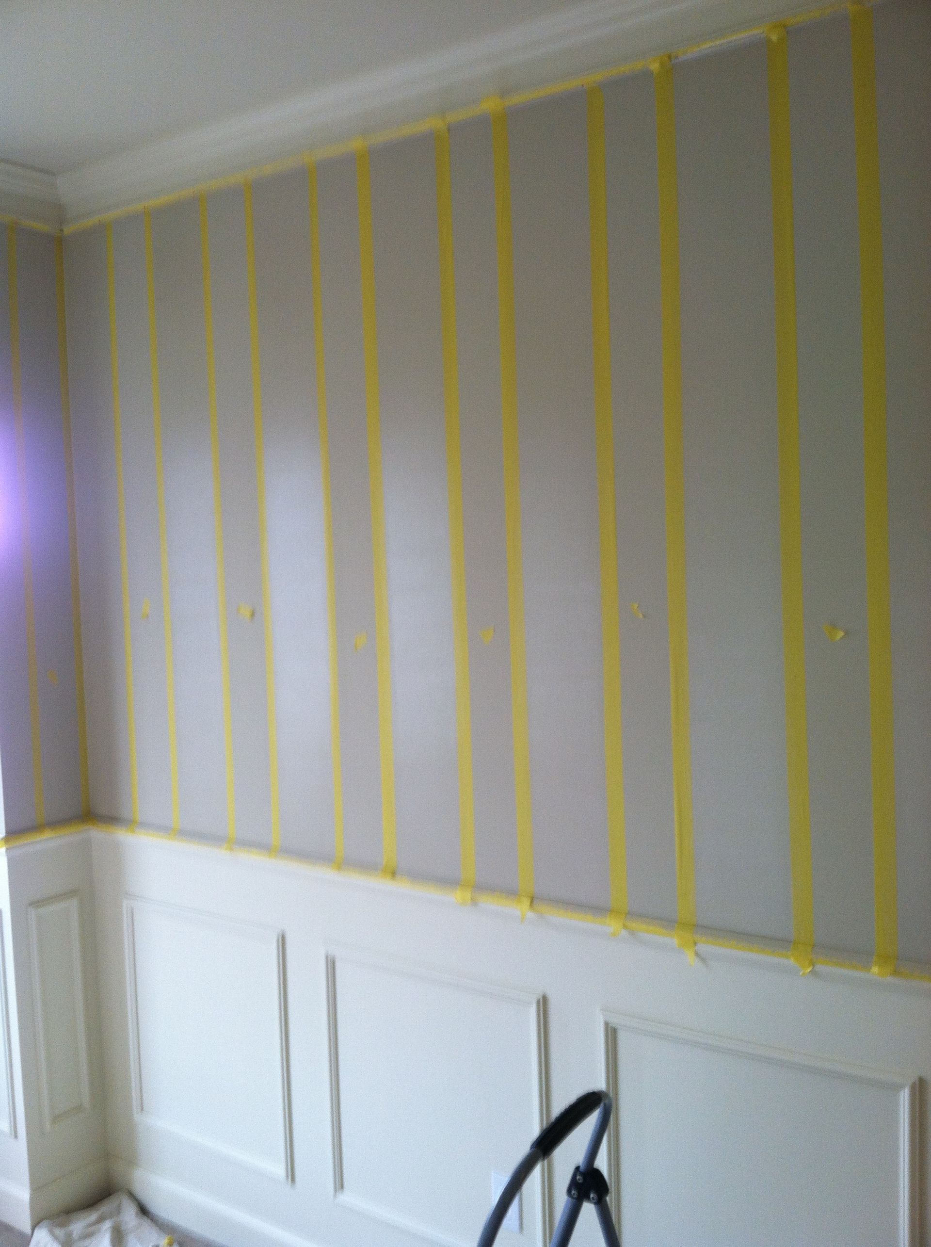 A room with a striped wall and yellow tape on it.