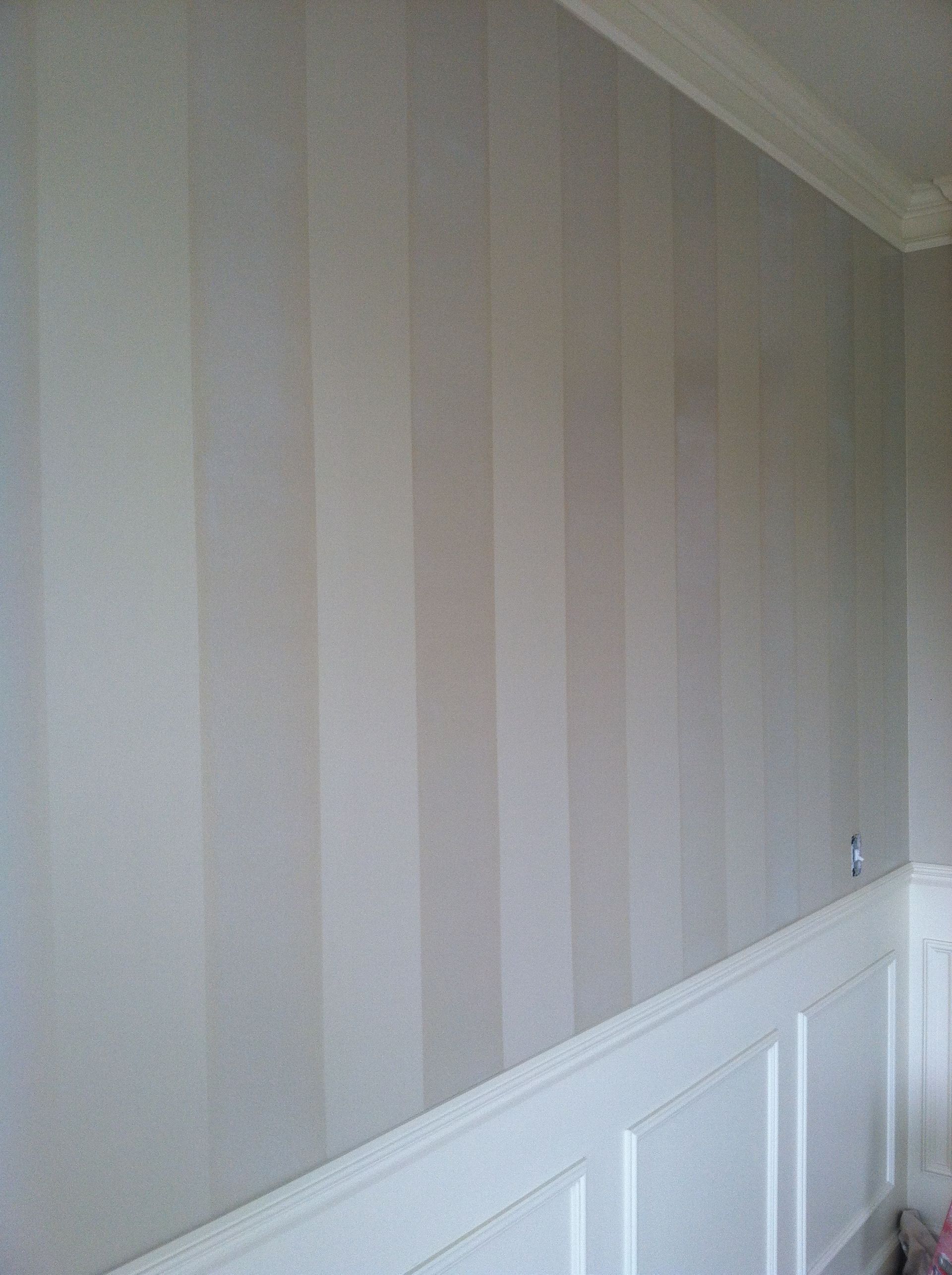 A wall with a striped wallpaper and white trim in a room.