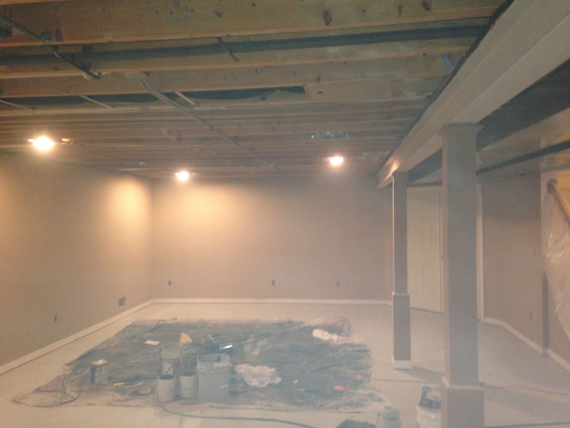 A basement under construction with a swimming pool in the middle of the room.