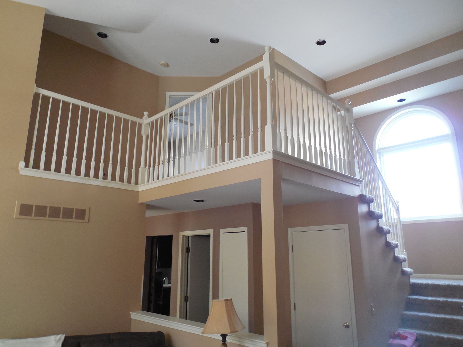 A living room with a balcony and stairs leading up to it