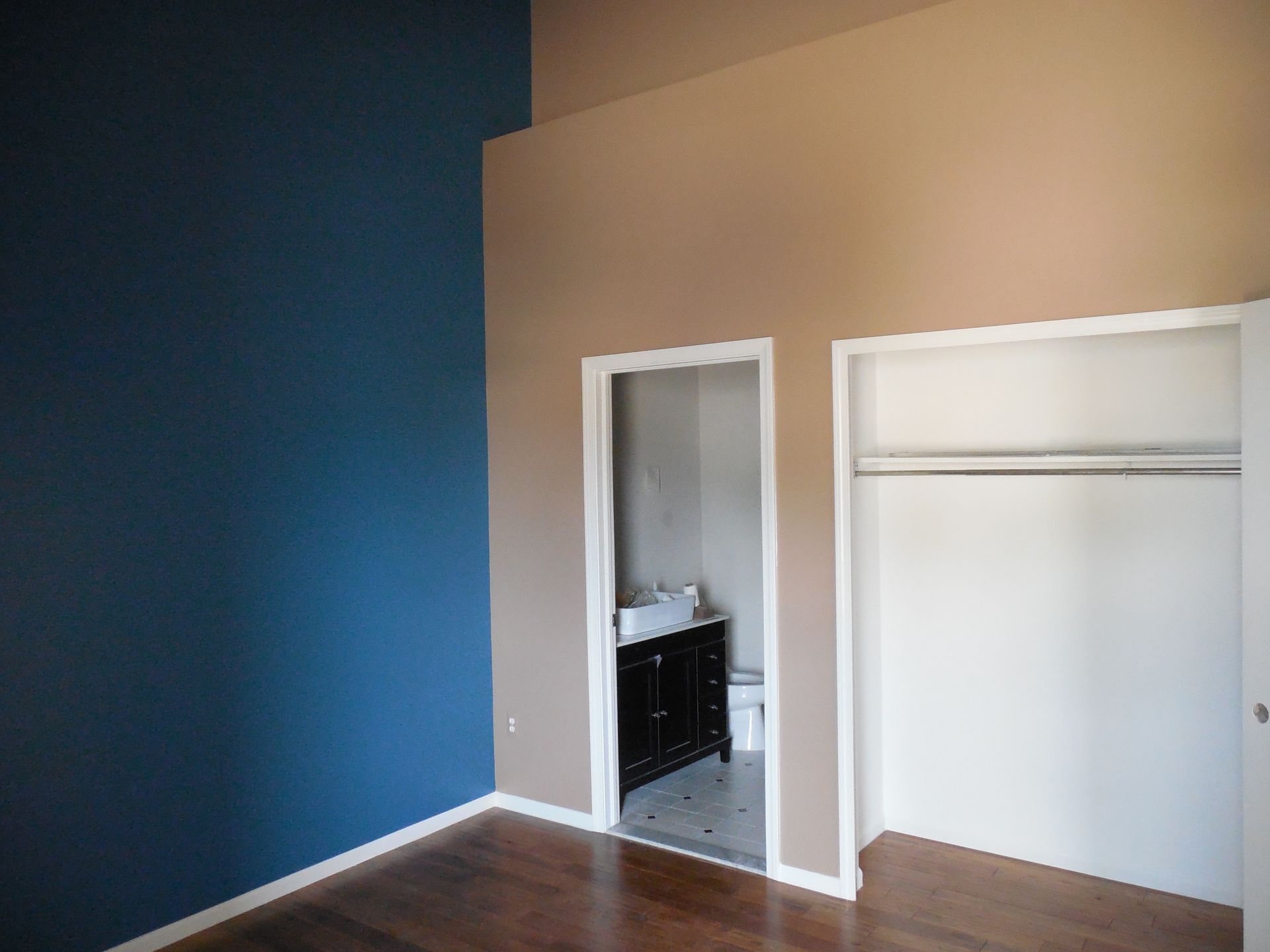 An empty room with blue walls and a bathroom in the background.