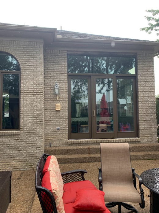 A patio with a couch and chairs in front of a house with sliding glass doors.