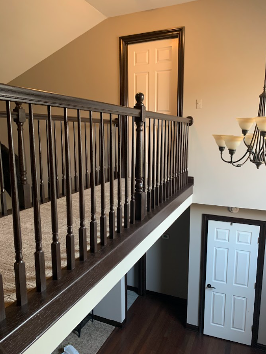 A staircase with a wooden railing and a white door