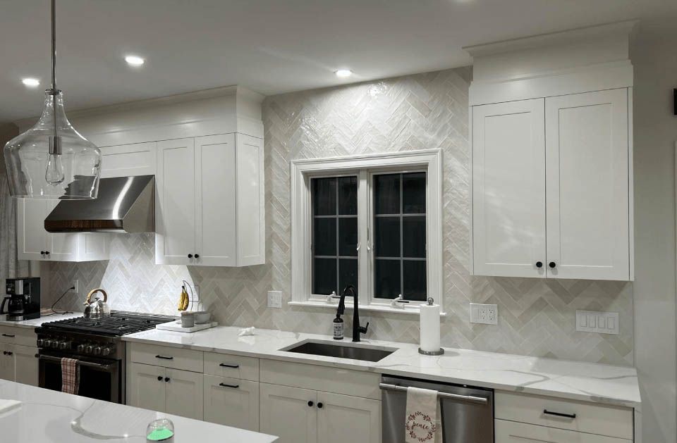 A kitchen with white cabinets , stainless steel appliances , a sink , and a window.