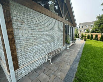 A white brick building with a bench in front of it.