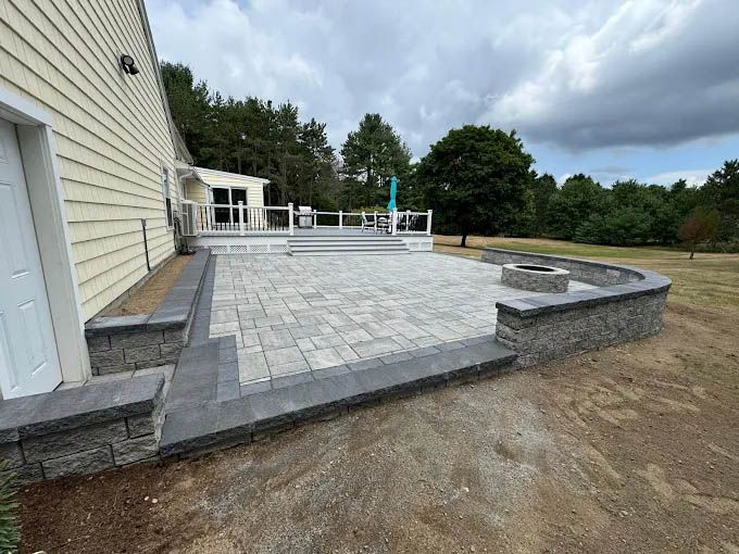 A patio with a fire pit in the middle of it next to a house.