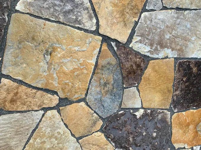 A close up of a stone wall with a lot of different colored rocks.
