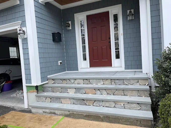 A blue house with a red door and stone steps.