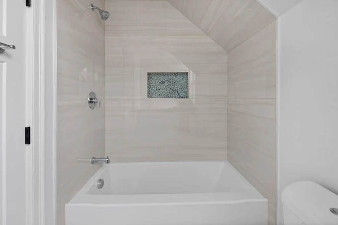 A bathroom with a bathtub , toilet and shower.