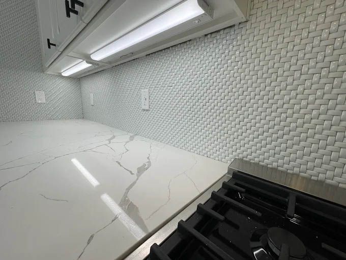 A kitchen with a stove top oven and a marble counter top.