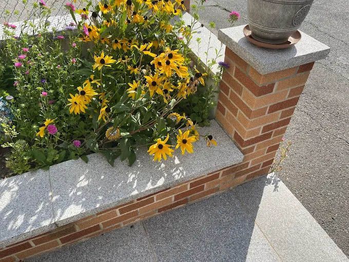 A brick wall with flowers in it and a pot on top of it