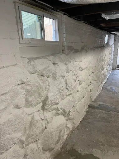 A stone wall in a basement with a window.