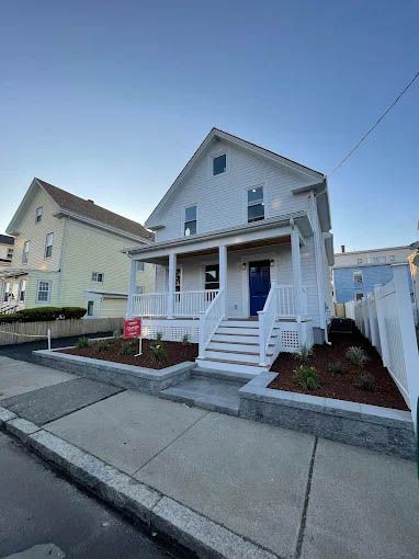 A white house with a blue door and stairs is for sale.