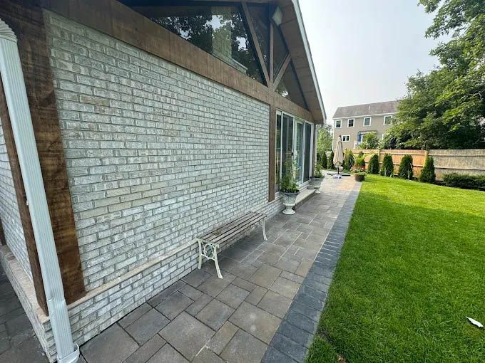 A white brick building with a bench in front of it.