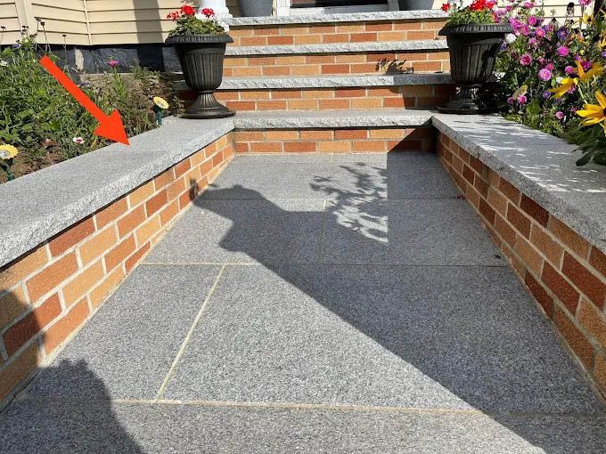 A brick walkway with stairs and flowers on the side