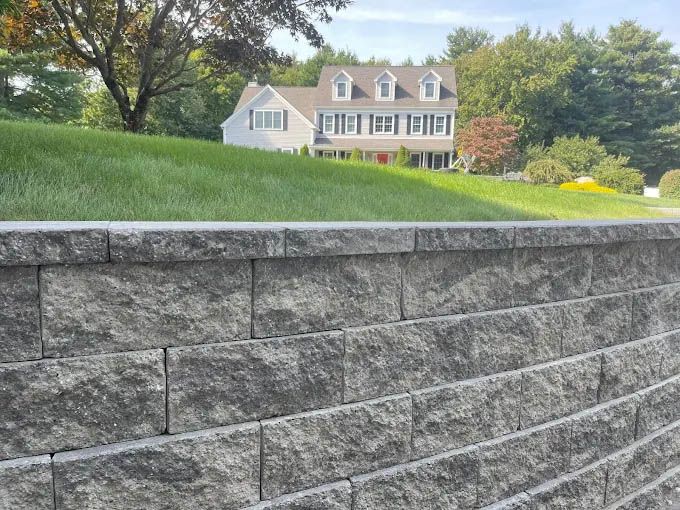 A brick wall with a house in the background