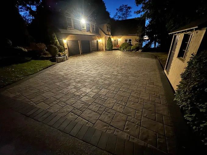 A brick driveway in front of a house at night.