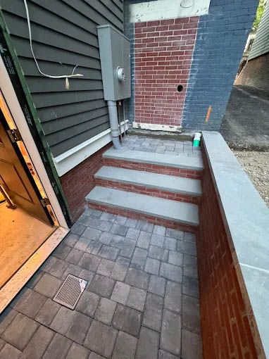 A brick wall with stairs leading up to it next to a garage door.