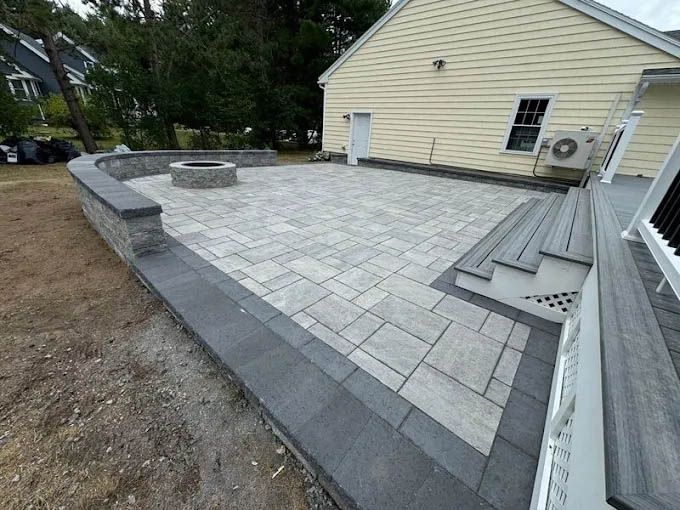 A patio with a fire pit and stairs in front of a house.