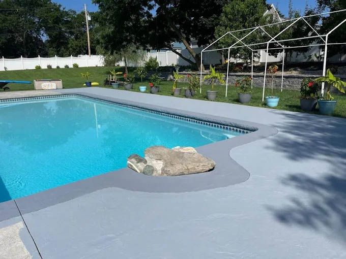 A large swimming pool surrounded by potted plants and trees